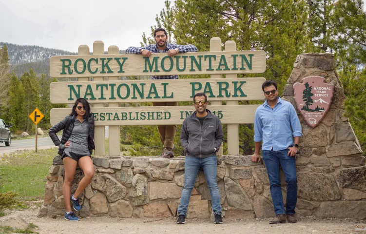 Three friends posing at the Rocky Mountain National Park entrance sign