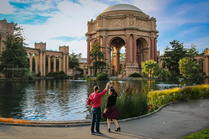A couple dancing on the walkway beside the lagoon at the Palace of Fine Arts, its rotunda and colonnade behind them.