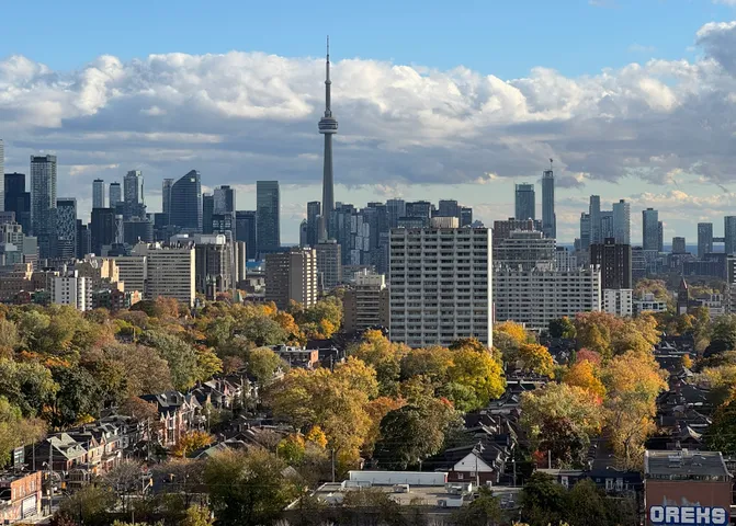 The Toronto skyline seen through autumn trees in full red and orange, viewed from Casa Loma.